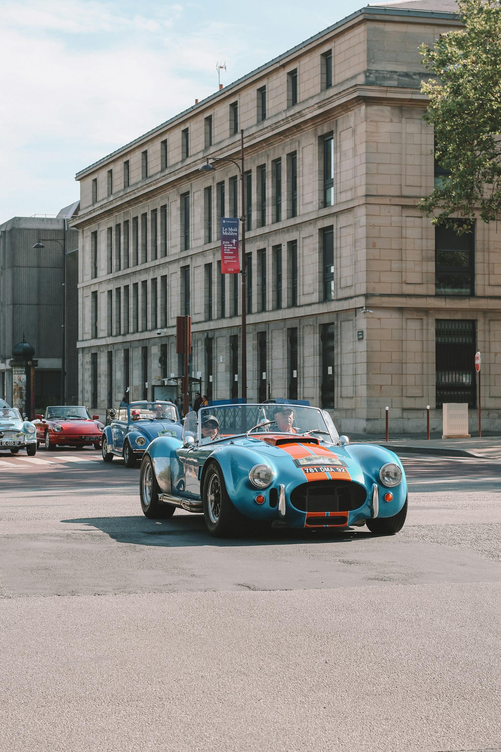 A blue-with-orange-stripe Cobra roadster in motion — the visual signature of @scottsrides.